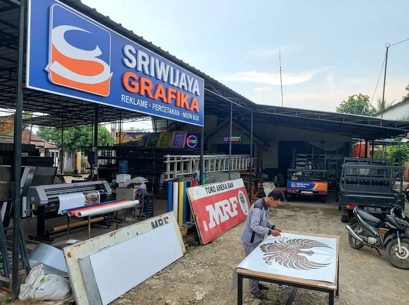Suasana workshop Sriwijaya Grafika di Talang Jambe dengan mesin laser cutting dan huruf timbul yang sedang diproduksi